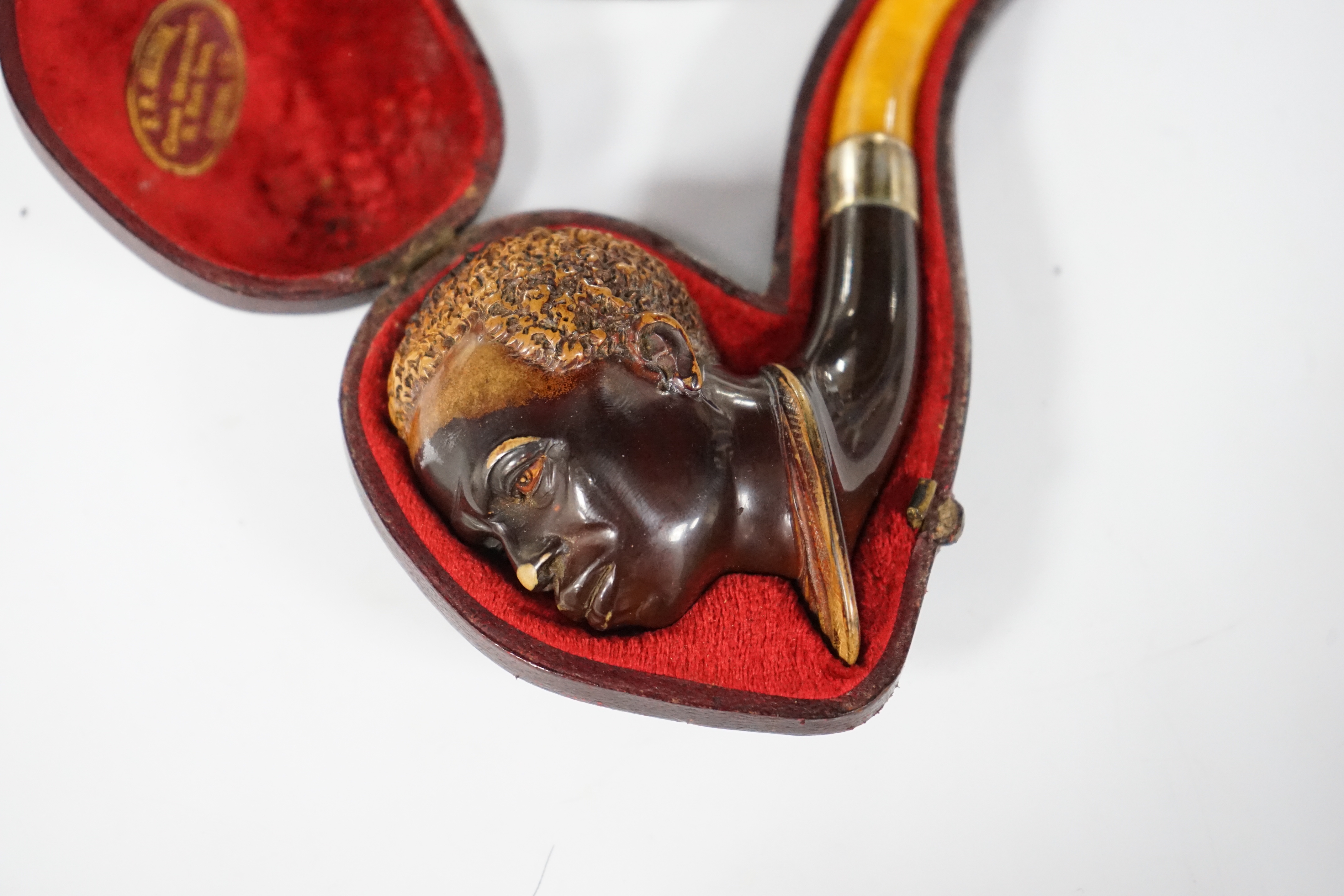 A cased Meerschaum pipe with a bowl modelled as a Nubian man’s head with metal mount and amber mouthpiece, 14cm long